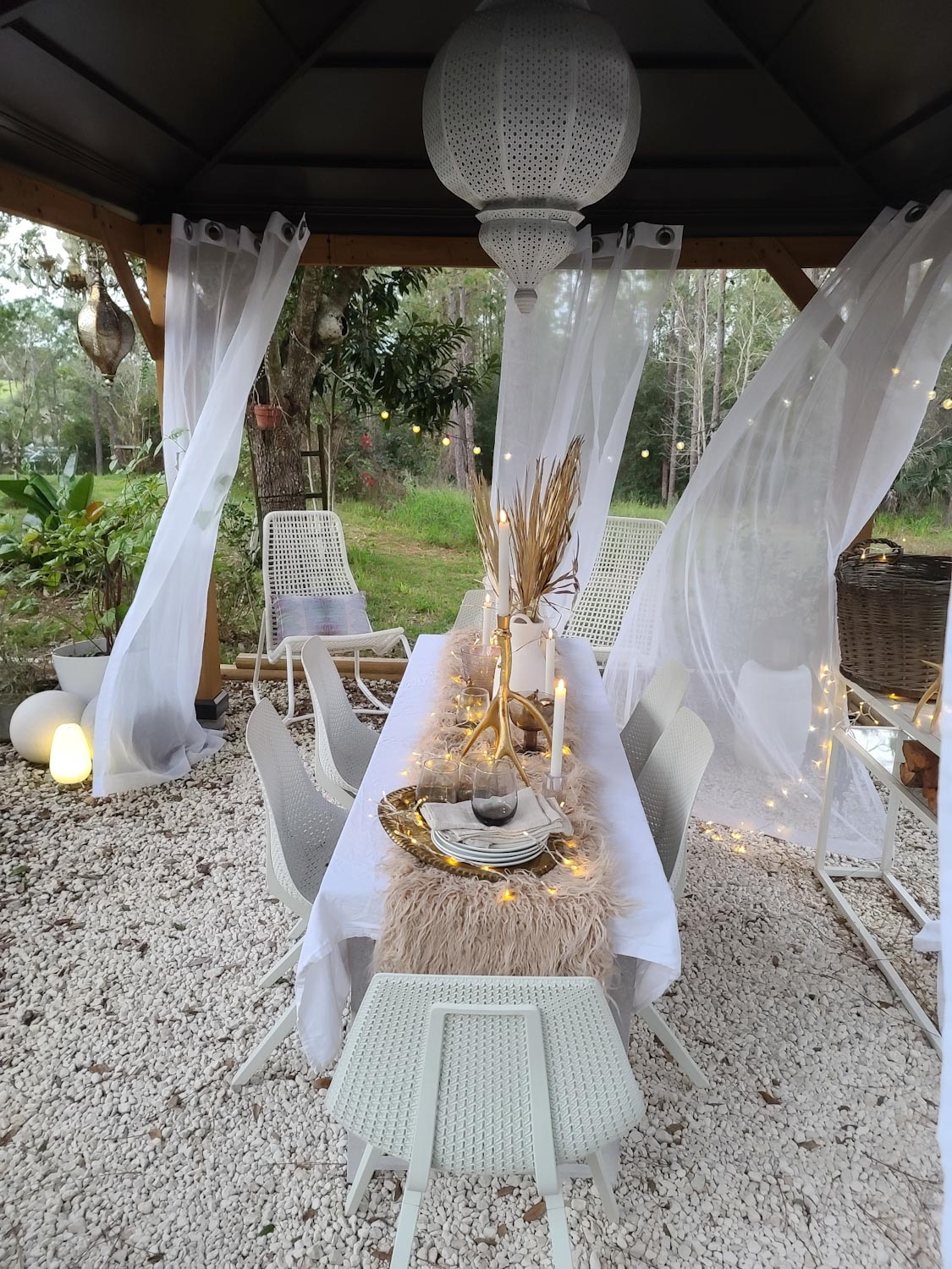 Cozy White Winter Wonderland Outdoor Dining space, flowing curtain and twinkle lights. 