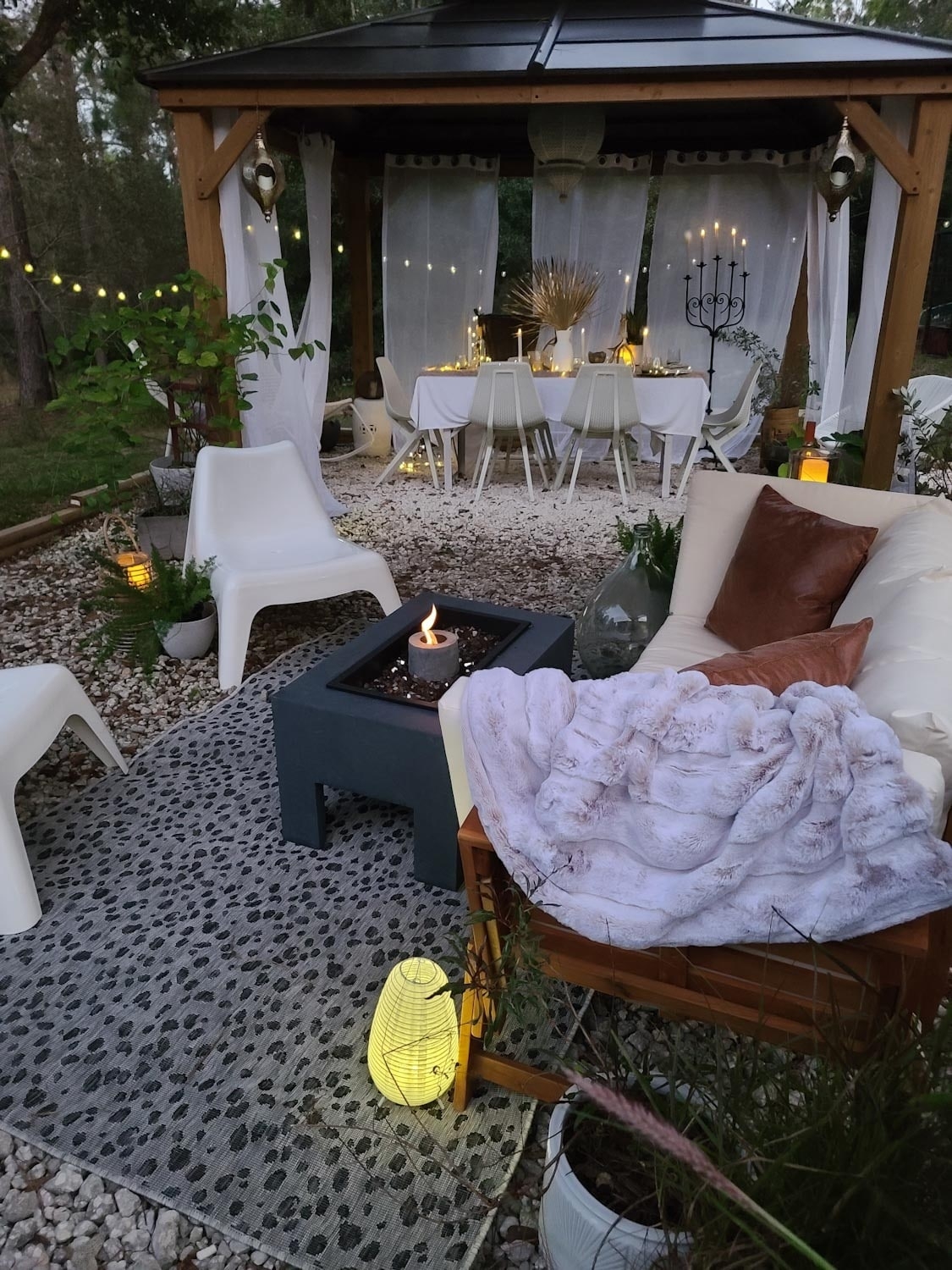 Outdoor dining space with fire pit, candles and lanterns. Twinkle lights, pillows and fur. Country living