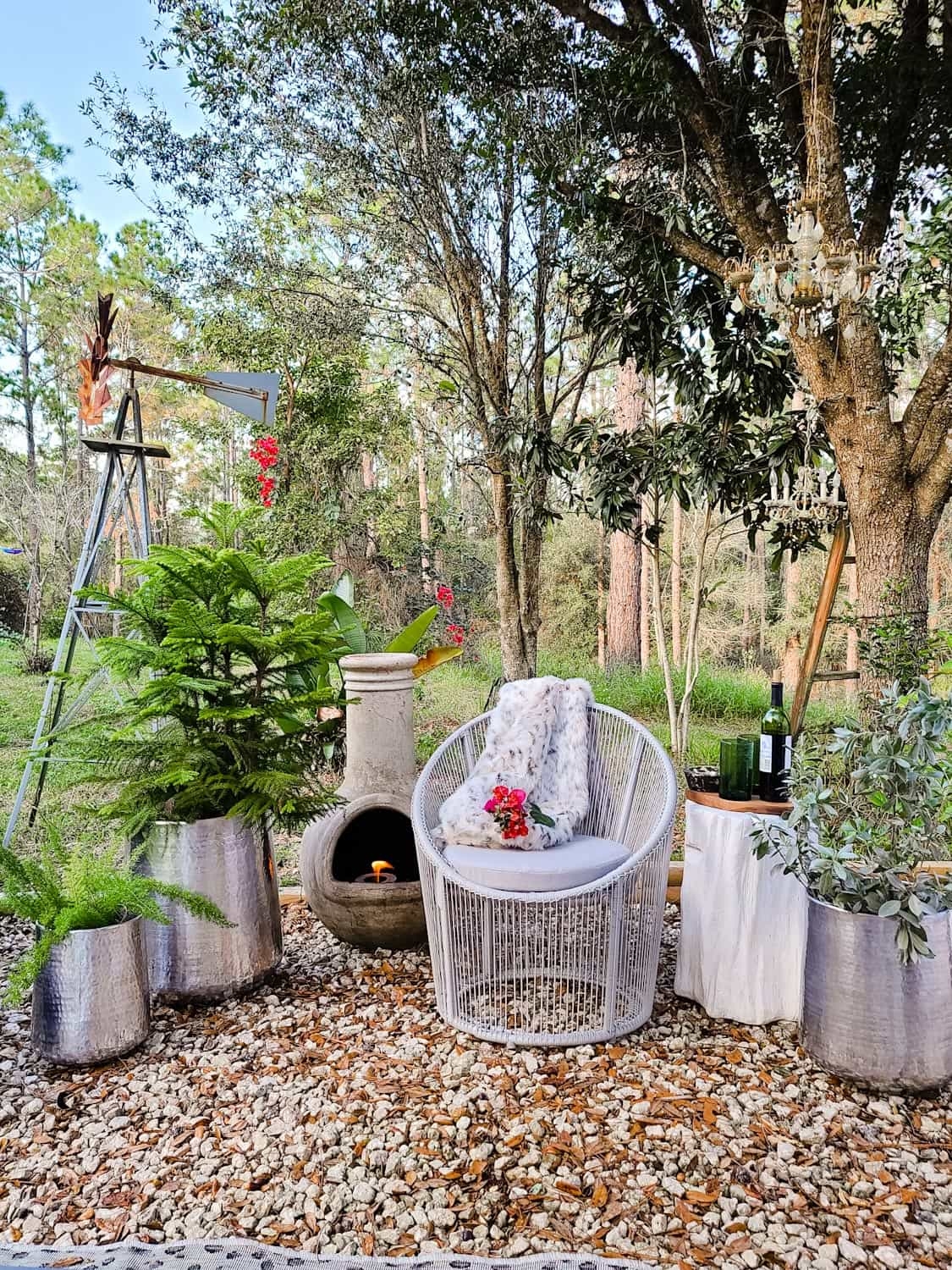 Cozy lounge space by the fire. Outdoor firepit, patio seating, scandibohostyle decor. Perfect winter decor and cozy spot for dinners,movie nights and social distanced gatherings. Hammered metal planters, green glassware.