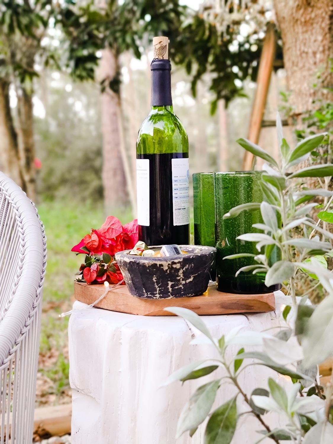 Cozy lounge space by the fire. Outdoor firepit, patio seating, scandibohostyle decor. Perfect winter decor and cozy spot for dinners,movie nights and social distanced gatherings. Hammered metal planters, green glassware.