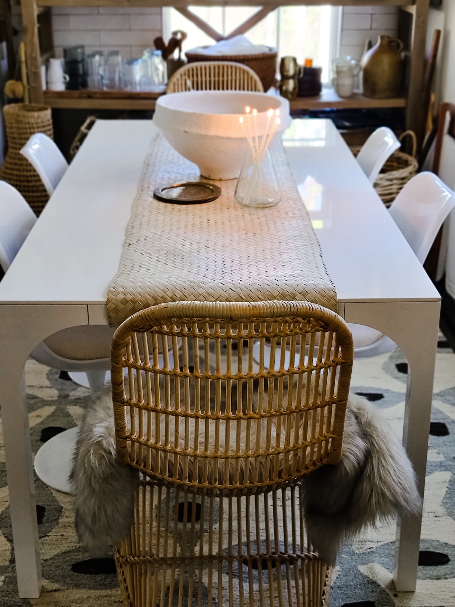 Scandinavian Modern Hygge style white dining room with candles texture woods and whites. Kitchen decor, vintage rugs, cane cabinet and open shelving.