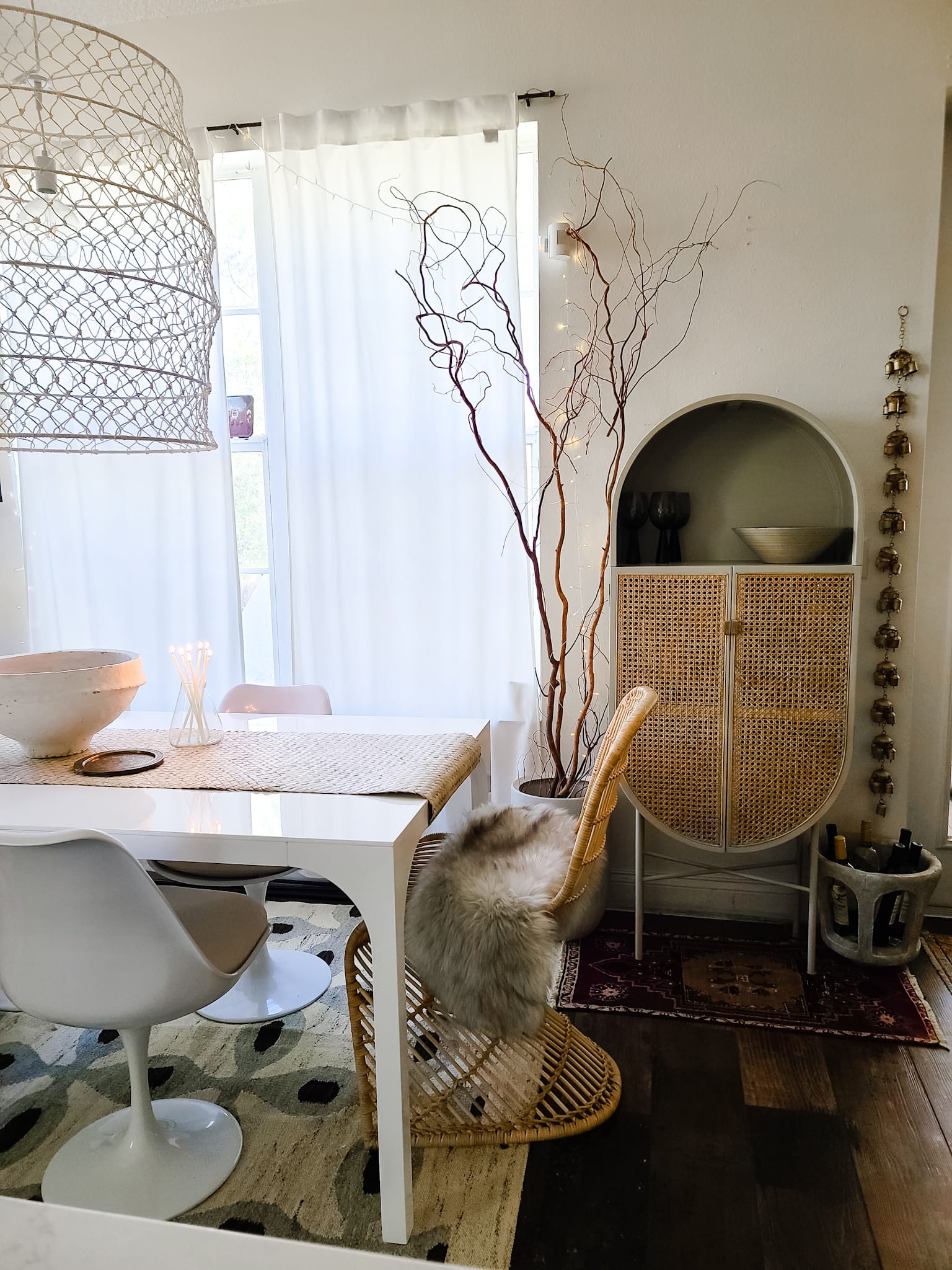 Scandinavian Modern Hygge style white dining room with candles texture woods and whites. Kitchen decor, vintage rugs, cane cabinet and open shelving.