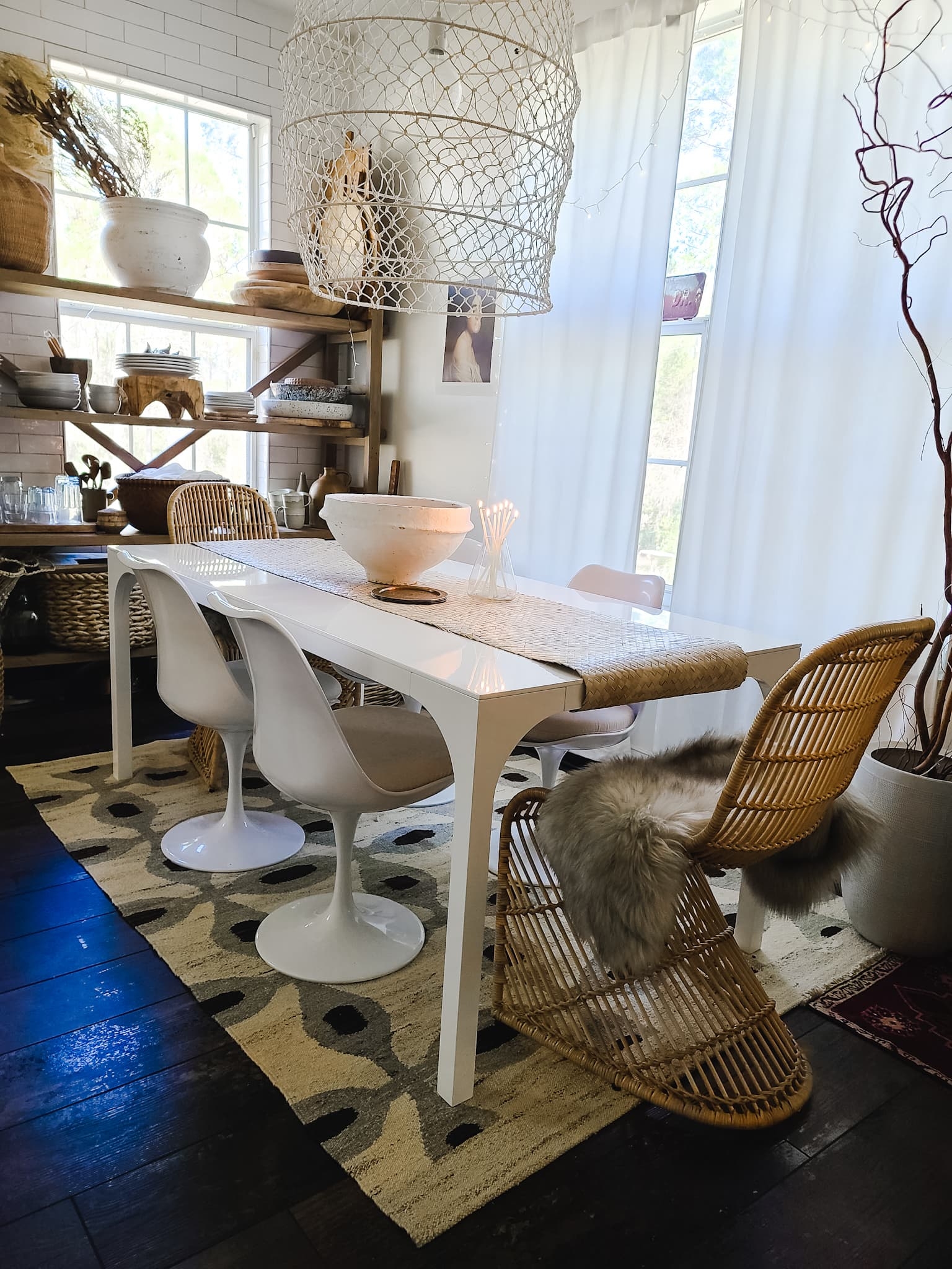 Scandinavian Modern Hygge style white dining room with candles texture woods and whites. Kitchen decor, vintage rugs, cane cabinet and open shelving.