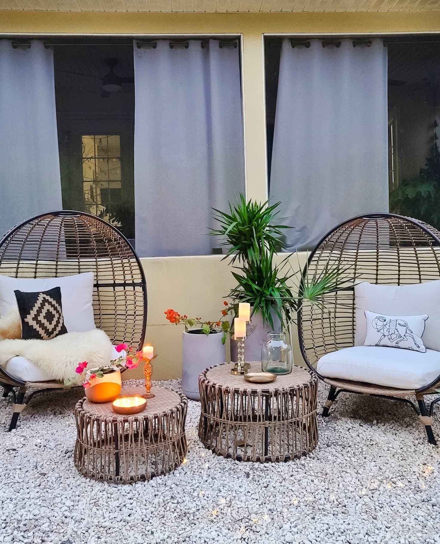 Backyard oasis patio egg chairs with wicker coffee tables gold accents flowers trees and boho chic decor