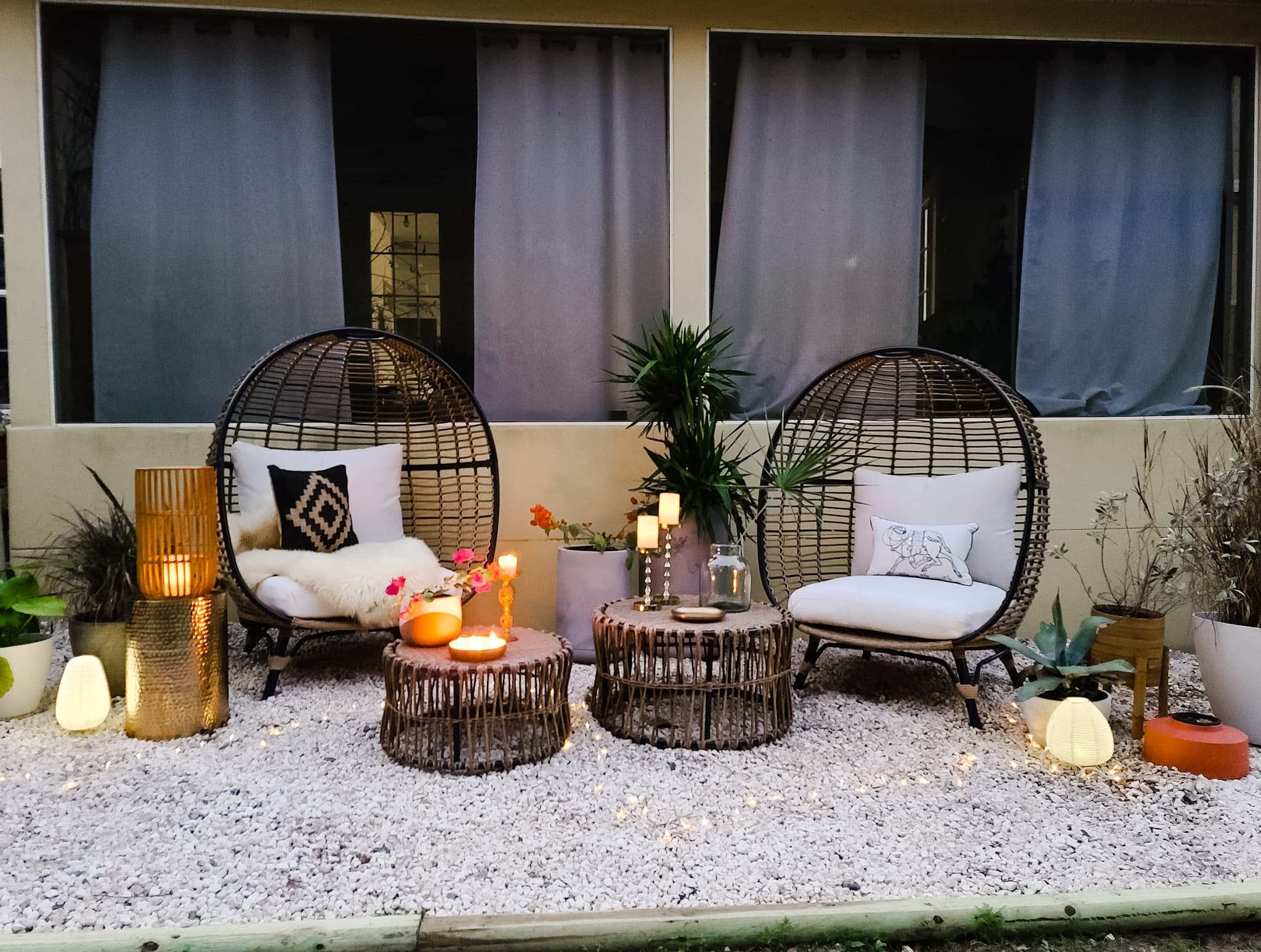 Backyard oasis patio egg chairs with wicker coffee tables gold accents flowers trees and boho chic decor