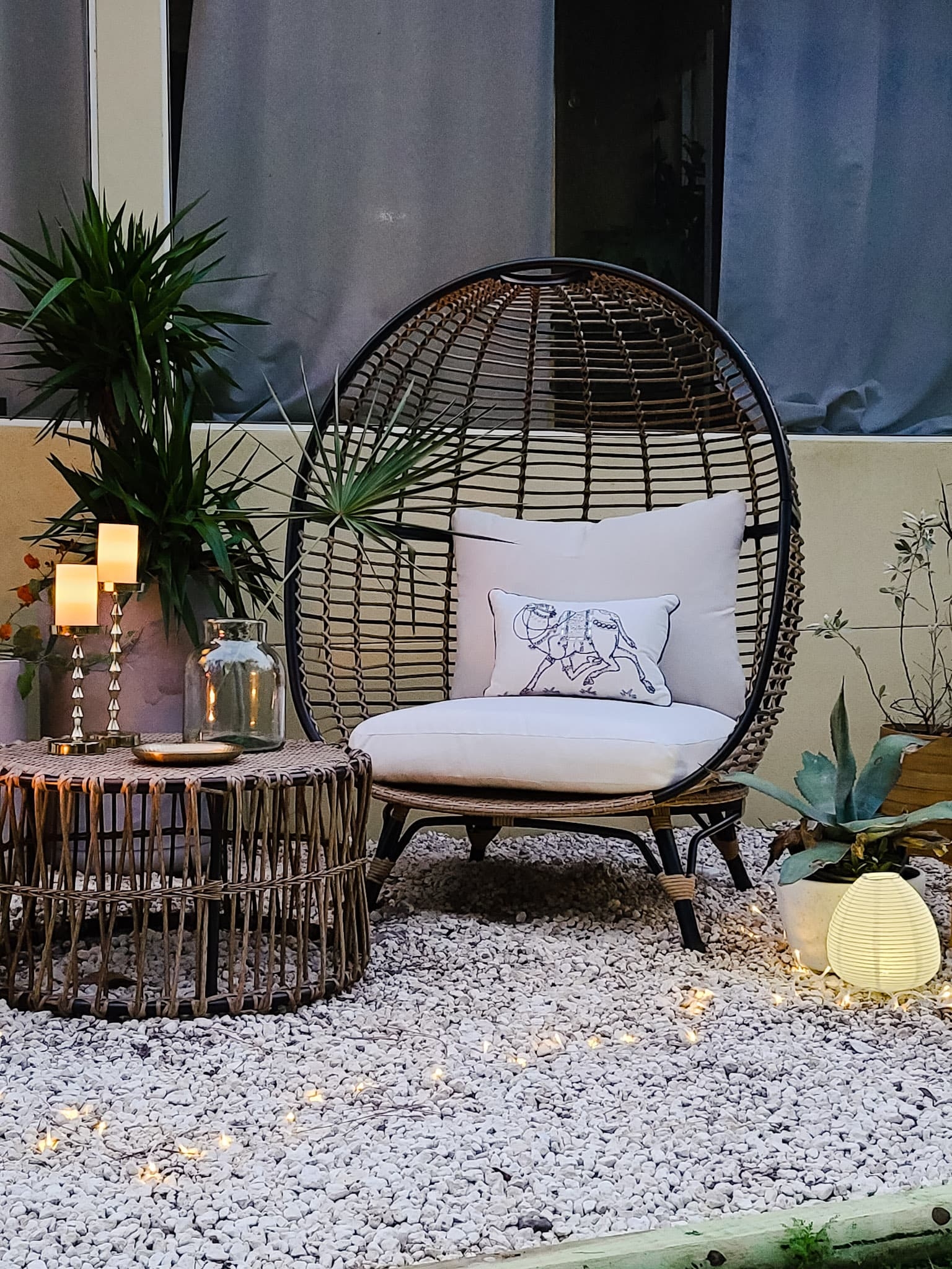 Backyard oasis patio egg chairs with wicker coffee tables gold accents flowers trees and boho chic decor