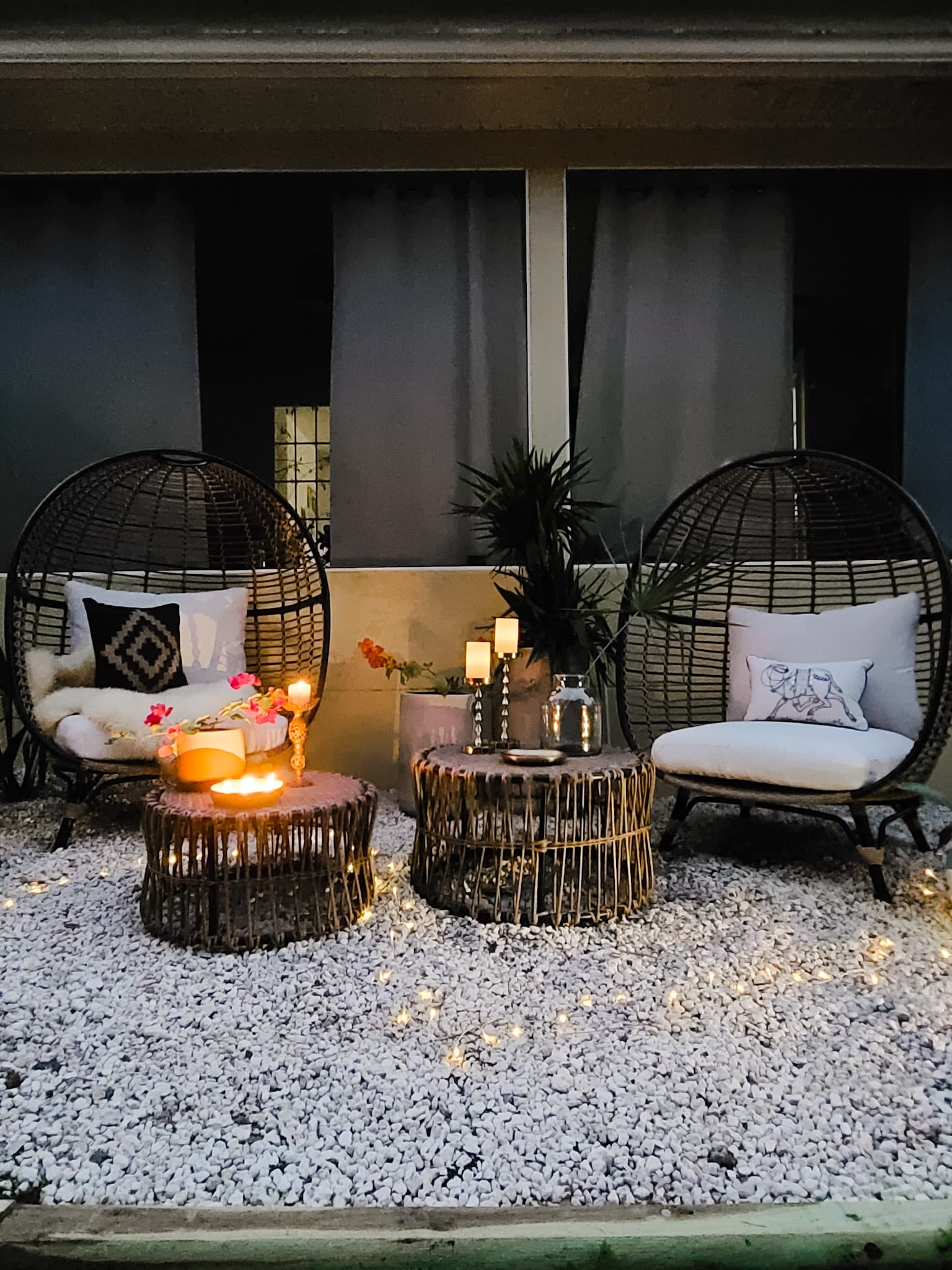 Backyard oasis patio egg chairs with wicker coffee tables gold accents flowers trees and boho chic decor